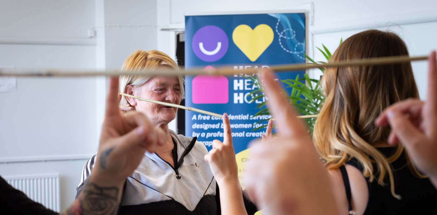 An image of two women playing the helium stick building game